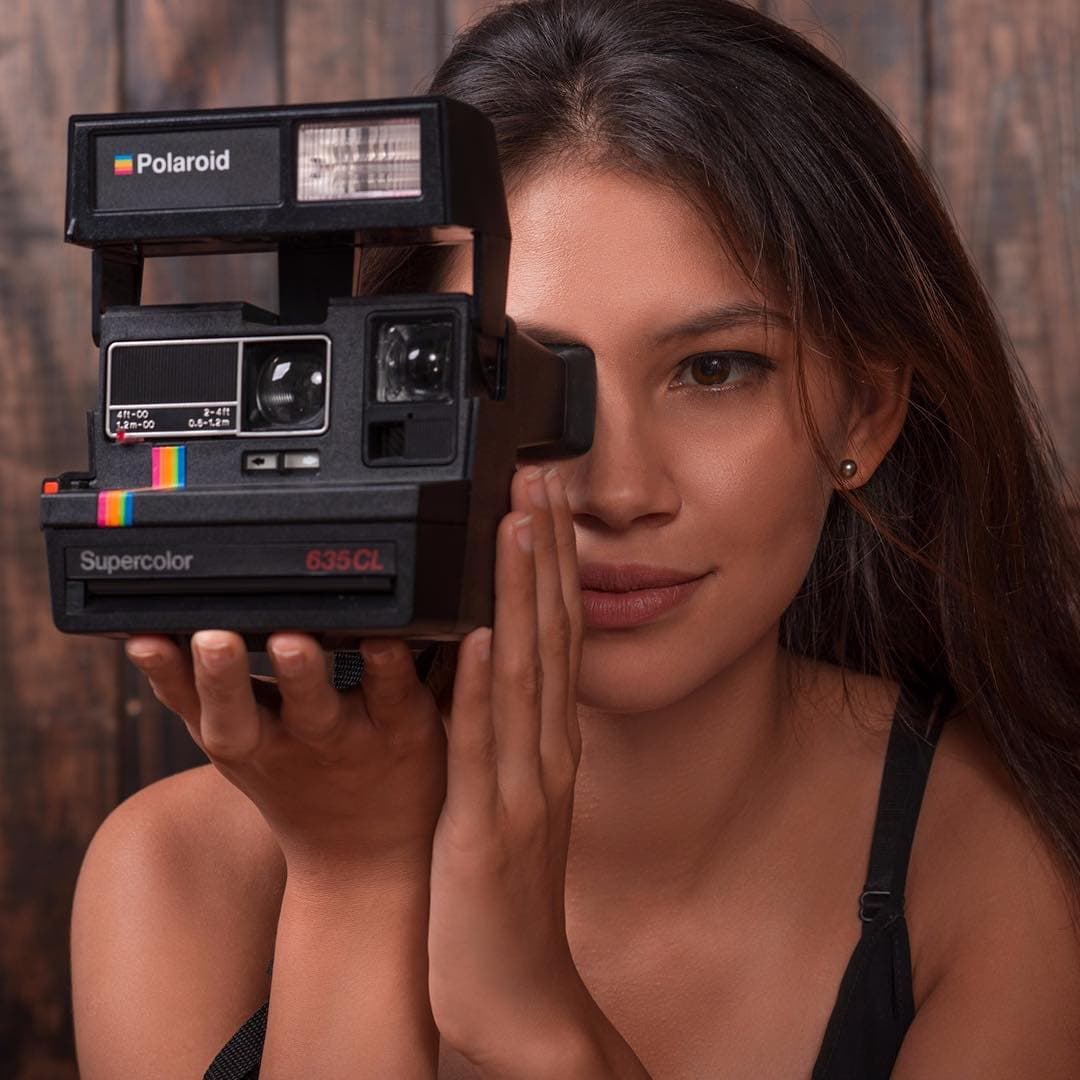 Joss posando con una camara polaroid.